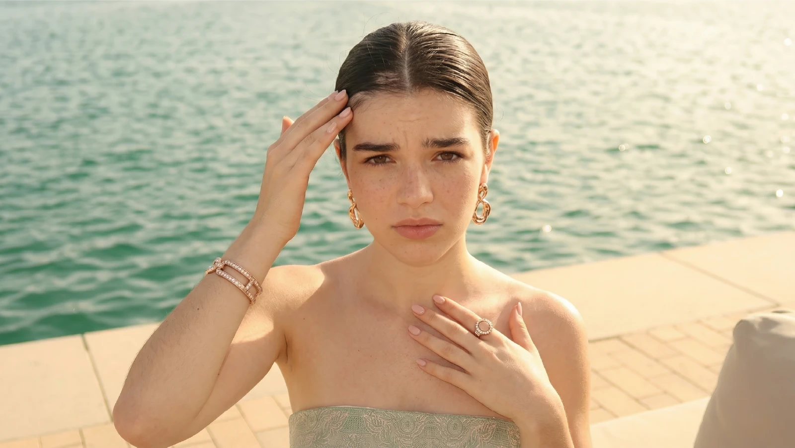 Woman with a tight slicked back bun showing scalp tension, traction alopecia and a concerned expression, illustrating potential hair damage from over-styling.