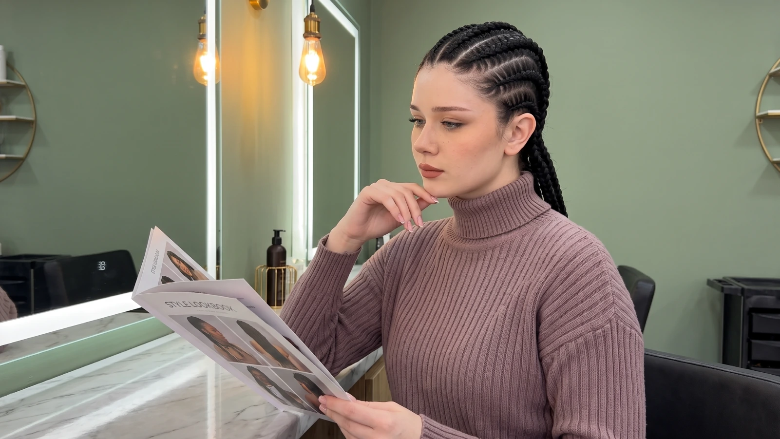 Woman with thick goddess braids reading a salon style lookbook