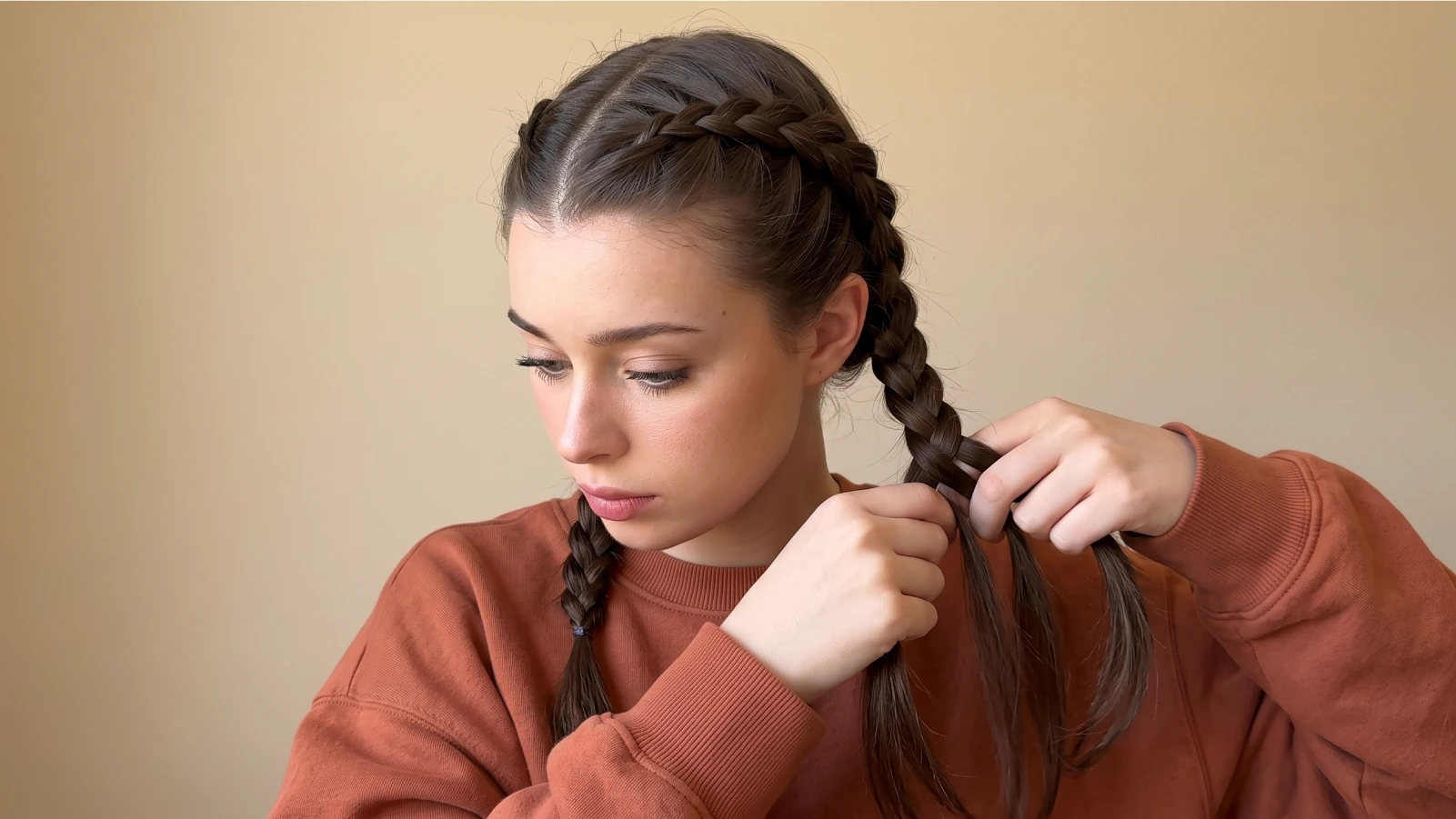 Woman Dutch braiding one side of her hair into a boxer braid from the front hairline back