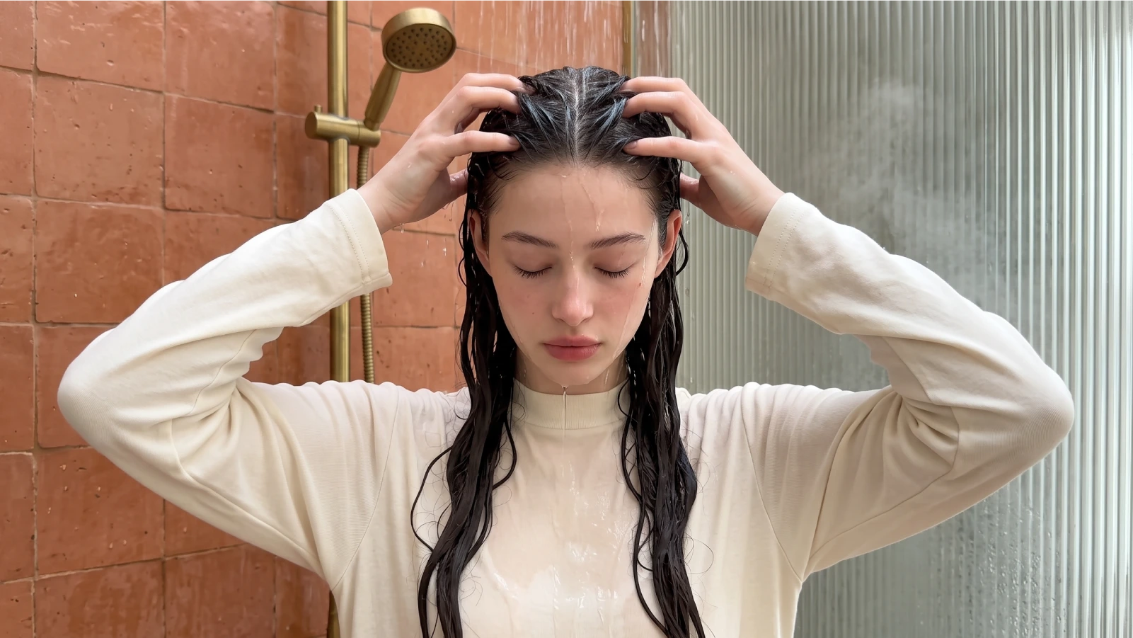 Woman massaging shampoo into her scalp with her fingertips in the shower